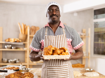 Happy male chef showing off croissants in his bakeryの写真素材