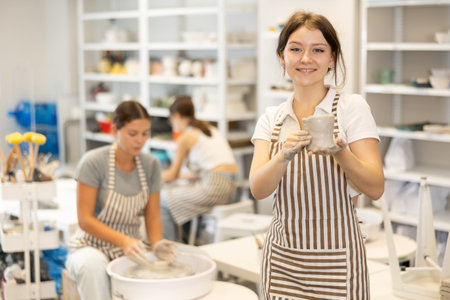 Young girl with handmade ceramic cup in workshop