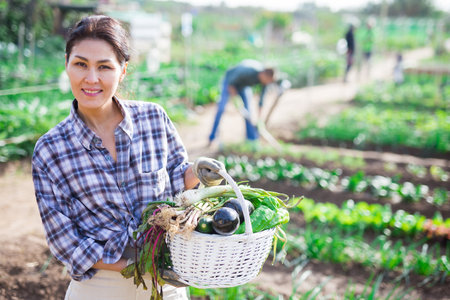 Woman farmer with harvest of ripe vegetablesの写真素材