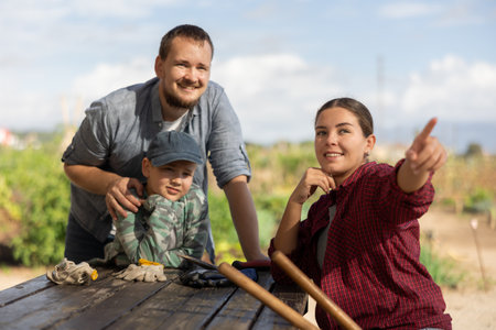 Man woman and boy looking at something in harvest fieldの写真素材