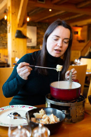 Woman having meal in Swiss restaurant, eating fondueの写真素材