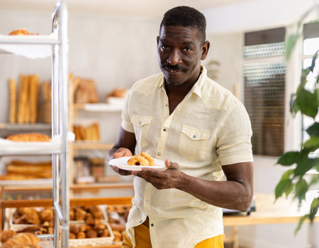 African man customer holding disposable plate with burger in bakeryの写真素材