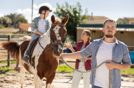 Young man leading horse with boy on horsebackの写真素材