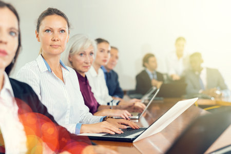 Middle aged businesswoman sitting at meeting and listening to presentationの写真素材