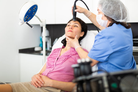Woman receiving facial electroporation procedure in aesthetic medicine office