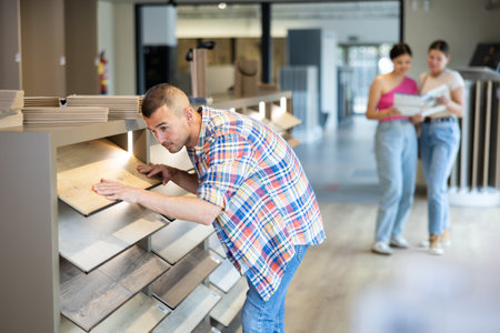 Young man choosing laminate flooring in storeの写真素材