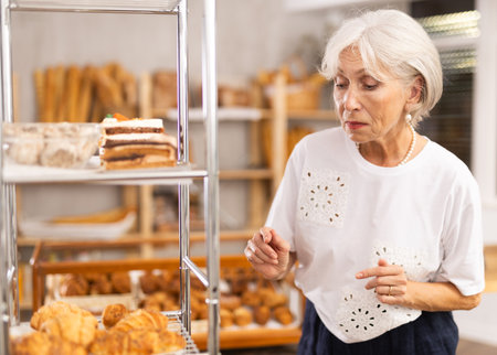 Woman in casual clothes chooses croissants for breakfast in bakeryの写真素材