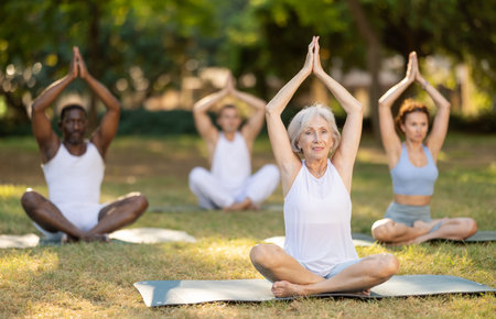 Yoga for people of different ages - elderly woman practicing different yoga poses together in parkの写真素材