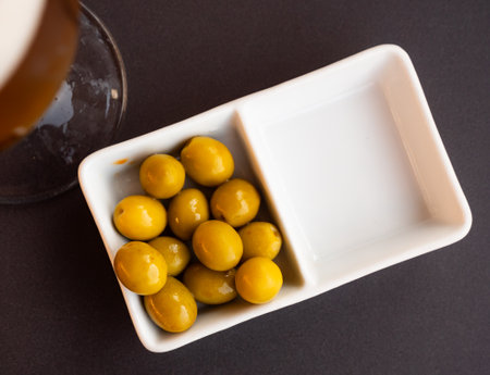 On white plate lies portion of large ripe green olives with stone.の写真素材