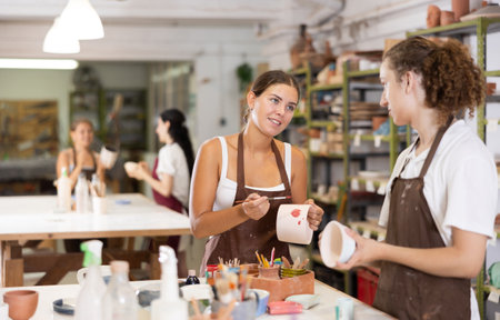 Young girl and guy painting with brush on handmade ceramic bowlの写真素材