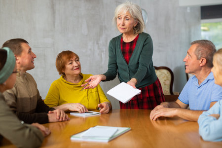 Elderly people communicating in language club with female tutorの写真素材