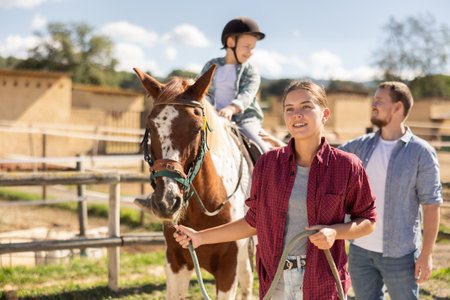 Young woman leading horse with boy on horsebackの写真素材