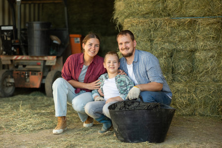 Portrait of happy family with son in backyard of horse farm, with hay in backgroundの写真素材