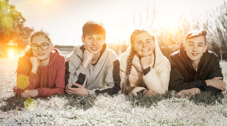 Smiling teenages lying on green grassの写真素材