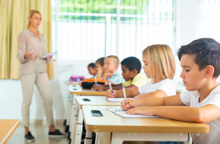 Diligent tweens studying in classroom with female teacherの写真素材