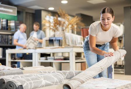 Young woman choosing carpet in building storeの写真素材