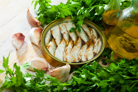 Canned small sardines in oil on background with greensの写真素材
