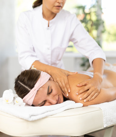 Young woman relaxing in spa center during back and shoulders massageの写真素材