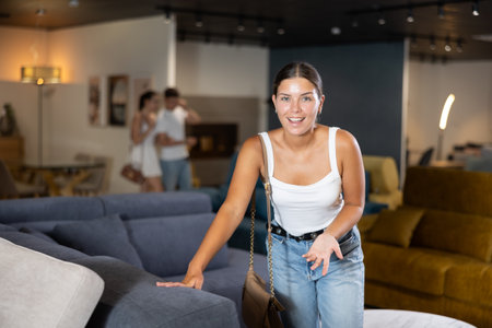 Young girl choosing convenient sofa in furniture shopの写真素材