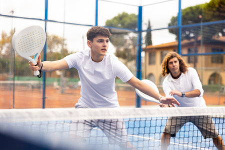Male player ready to hit the ball while playing padel on hard courtの写真素材