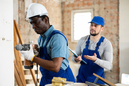 African-american man builder using electric hammer in construction siteの写真素材
