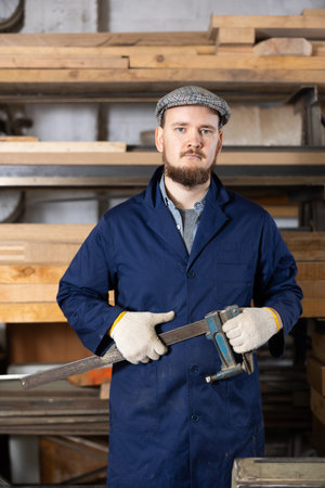Young man carpenter posing in wood workshop