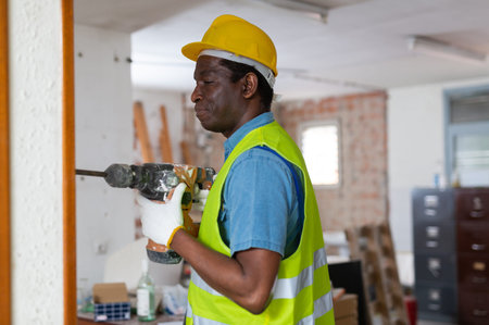 Focused african american builder working with pneumatic jackhammer