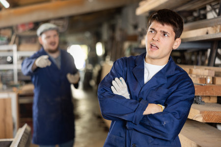 Owner of furniture factory confronts a worker in the workshopの写真素材
