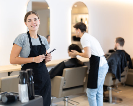 Young female hairdresser with comb and electric razorの写真素材