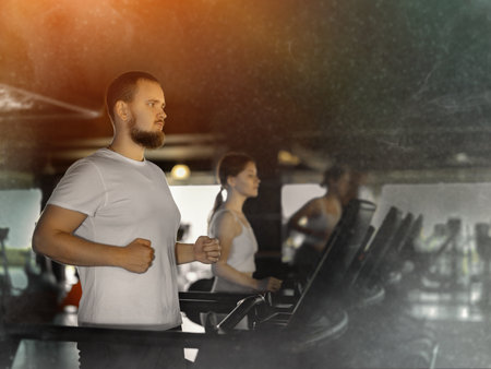Guy in gym runs with help of treadmillの写真素材