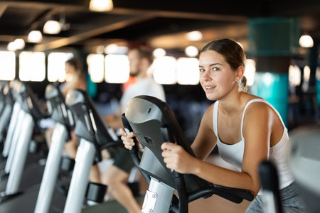 Young woman exercising on exercise bike in gym
