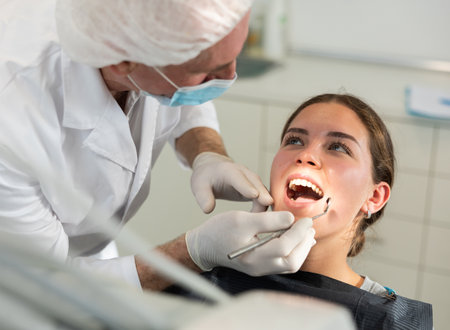 Elderly male dentist examining female patientの写真素材