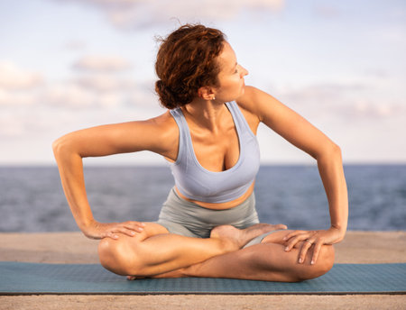 Experienced female trainer doing various exercises to warm up the body before yoga classes on...