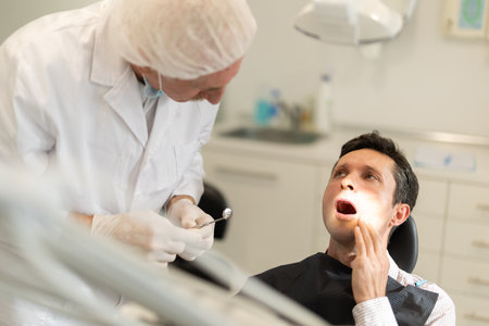 Elderly male dentist examining male patientの写真素材