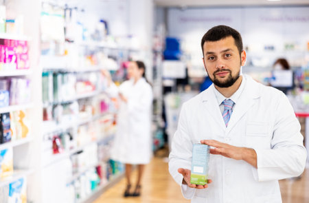 Portrait of man druggist in drugstore with drug packageの写真素材