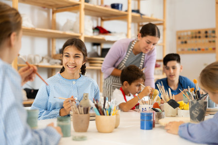 Children painting ceramics with a teacher