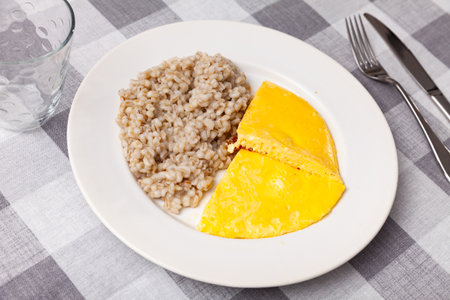Boiled pearl barley with omelette served on dish on checkered clothの写真素材