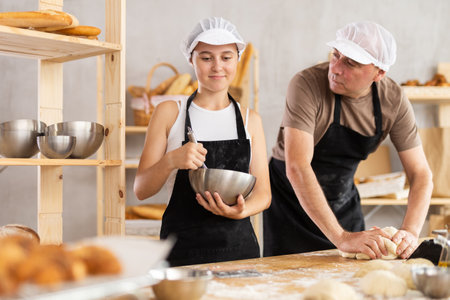 Girl and man bakers knead and whisk doughの写真素材