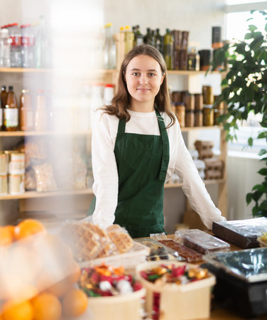Teenage girl seller at counter in grocery storeの写真素材
