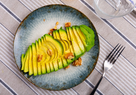 Appetizing avocado and walnuts at table
