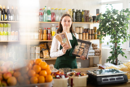 Teenage girl seller offers sweets in grocery storeの写真素材