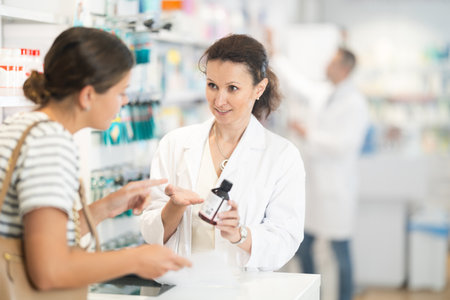 A pharmacist consulting with a customer about medication at a pharmacy counterの写真素材