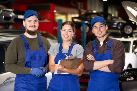 Three mechanics holding paperwork standing in auto service shop