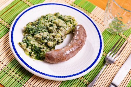 Fatty fried homemade pork weenie sausage with side dish of pearl barley with spinach.の写真素材