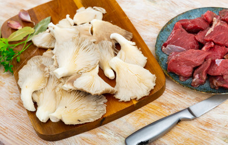 Pieces of raw veal meat, spices and oyster mushrooms.の写真素材