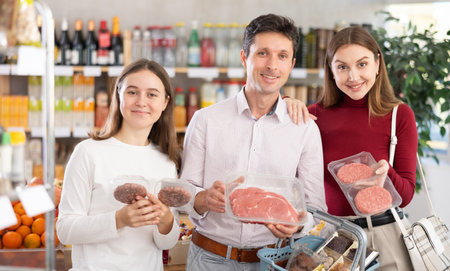 Family with teenage girl choosing hamburger or beef entrecote in groceryの写真素材