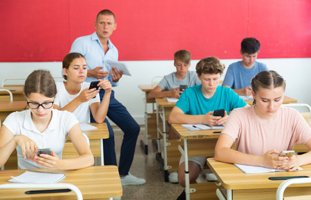 Teenager students sitting in class room with smartphonesの写真素材