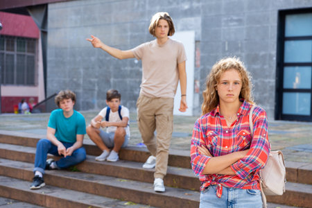 Upset girl in front of her friends after quarrel on streetの写真素材