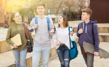 Carefree teen students walking outside school
