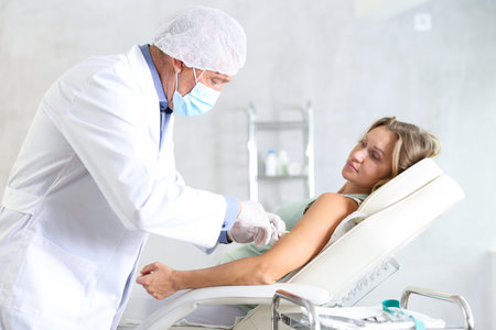 Man doctor makes an injection in arm of womanの写真素材